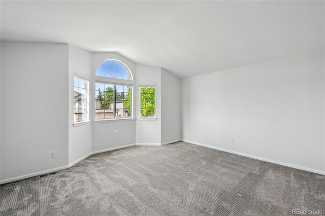 unfurnished room featuring carpet floors, lofted ceiling, and baseboards