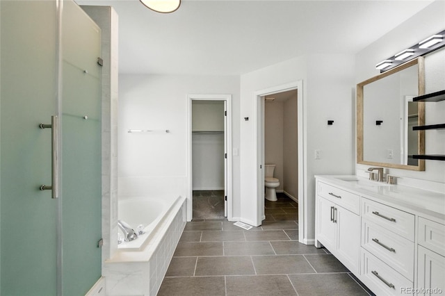 full bathroom featuring toilet, a bath, vanity, tile patterned floors, and baseboards