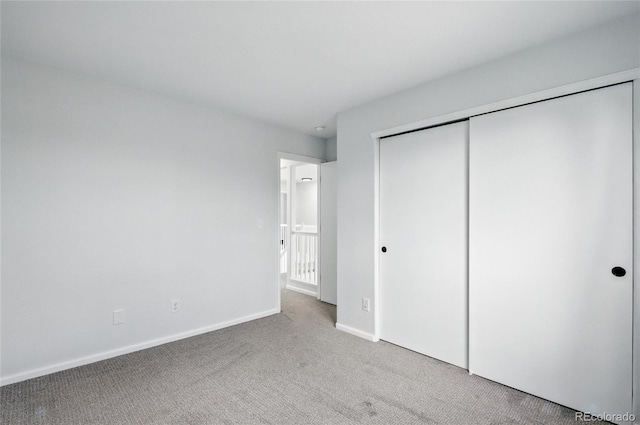 unfurnished bedroom with carpet, baseboards, and a closet