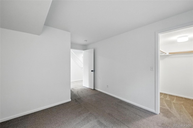 unfurnished bedroom with a walk in closet, carpet, baseboards, and a closet