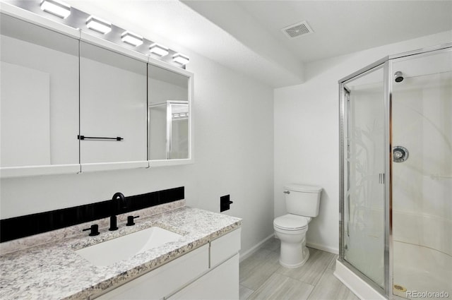 full bathroom with a stall shower, toilet, baseboards, and vanity