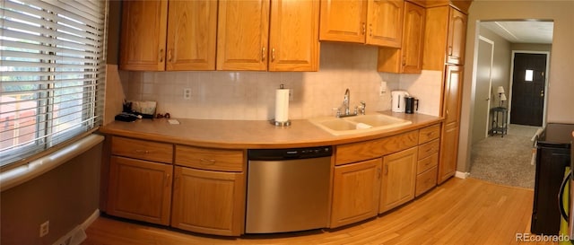 kitchen with tasteful backsplash, sink, light hardwood / wood-style flooring, and stainless steel dishwasher