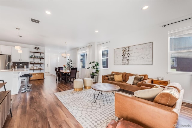 living room with dark wood-type flooring and a chandelier