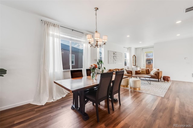 dining area featuring dark wood-type flooring and an inviting chandelier