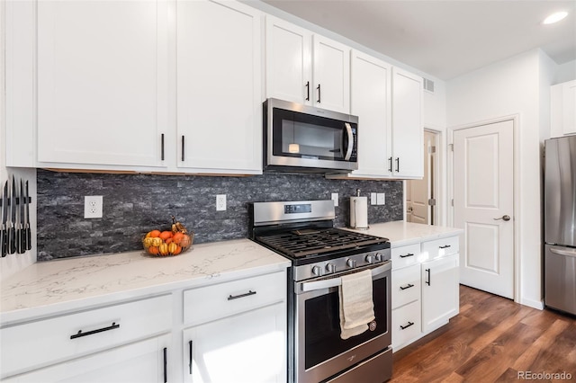 kitchen with white cabinetry, backsplash, stainless steel appliances, light stone countertops, and dark hardwood / wood-style flooring