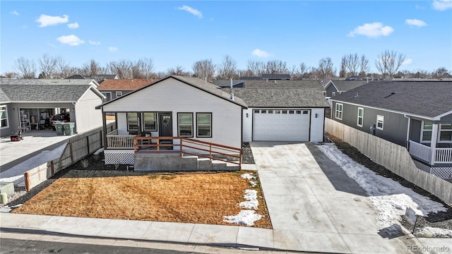 view of front facade with driveway, a residential view, an attached garage, fence, and a porch