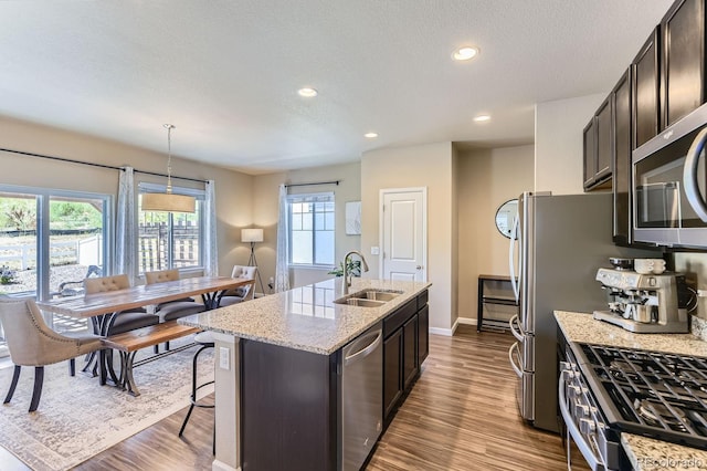 12851 Billingsley Trl, Parker, CO 80134 - kitchen featuring stainless steel appliances, a kitchen island with sink, dark wood finished floors, healthy amount of natural light, and recessed lighting