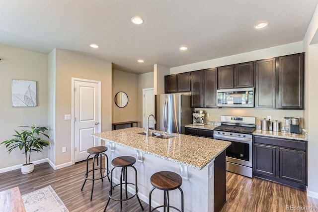 12851 Billingsley Trl, Parker, CO 80134 - kitchen with appliances with stainless steel finishes, dark wood-type flooring, a kitchen breakfast bar, a center island with sink, and dark brown cabinets