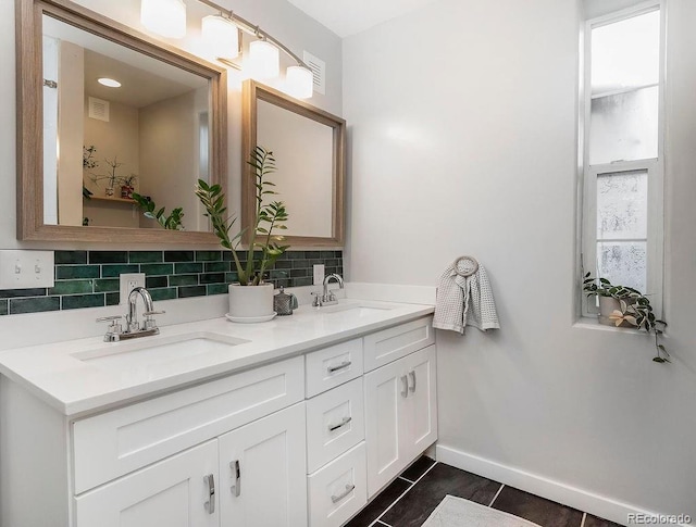 bathroom with decorative backsplash, double vanity, baseboards, and a sink