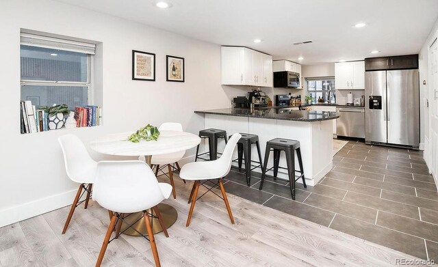 kitchen featuring recessed lighting, a kitchen breakfast bar, appliances with stainless steel finishes, a peninsula, and white cabinets