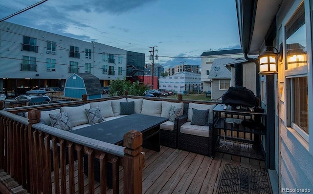 wooden terrace with an outdoor living space, a storage unit, and an outdoor structure