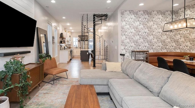 living area with an accent wall, recessed lighting, and light wood-style floors