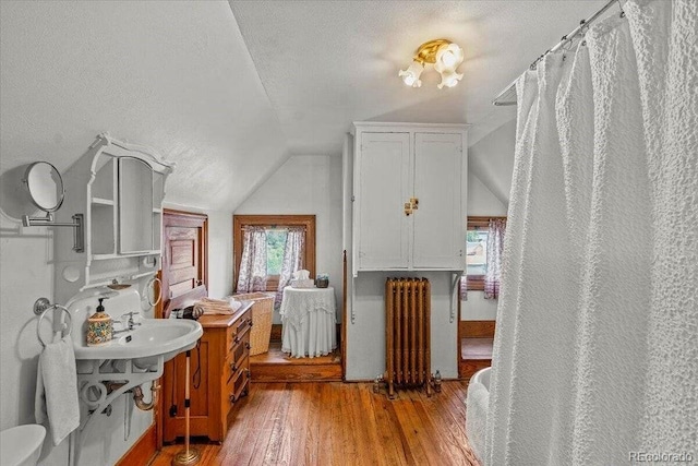 310 E 2nd St, Trinidad, CO 81082 - bathroom with radiator, vaulted ceiling, wood finished floors, and a textured ceiling