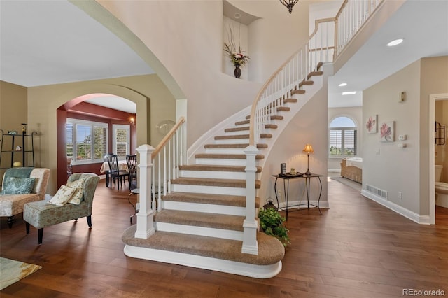 7056 S Owens St, Littleton, CO 80127 - staircase with hardwood / wood-style floors, baseboards, a high ceiling, recessed lighting, and arched walkways