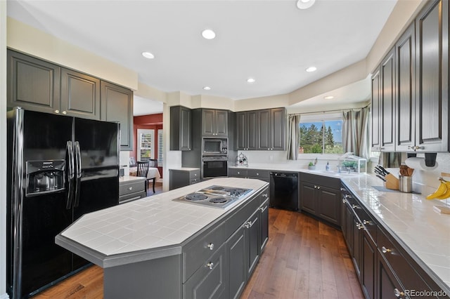 7056 S Owens St, Littleton, CO 80127 - kitchen with black appliances, tile countertops, a kitchen island, a sink, and dark wood-style flooring