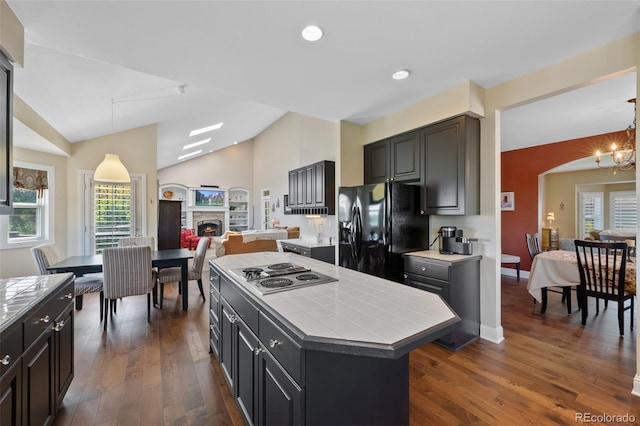 7056 S Owens St, Littleton, CO 80127 - kitchen with tile counters, black fridge with ice dispenser, stainless steel electric stovetop, lofted ceiling, and open floor plan