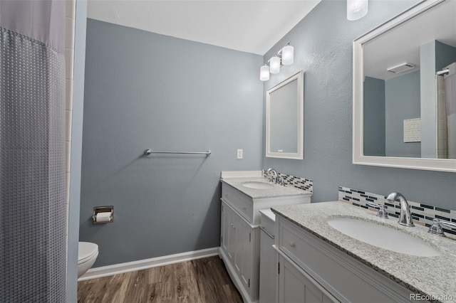 7056 S Owens St, Littleton, CO 80127 - bathroom featuring wood finished floors, two vanities, toilet, baseboards, and a shower with shower curtain