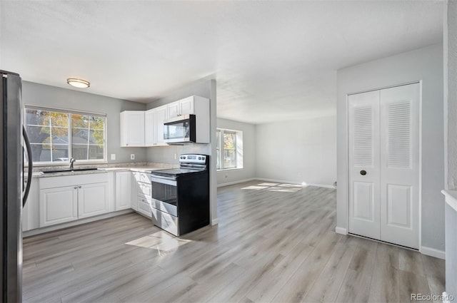 kitchen featuring sink, light hardwood / wood-style flooring, white cabinets, and appliances with stainless steel finishes