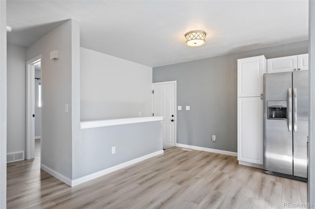 kitchen featuring stainless steel fridge, light hardwood / wood-style floors, and white cabinets