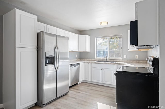 kitchen with appliances with stainless steel finishes, sink, white cabinets, and light hardwood / wood-style floors