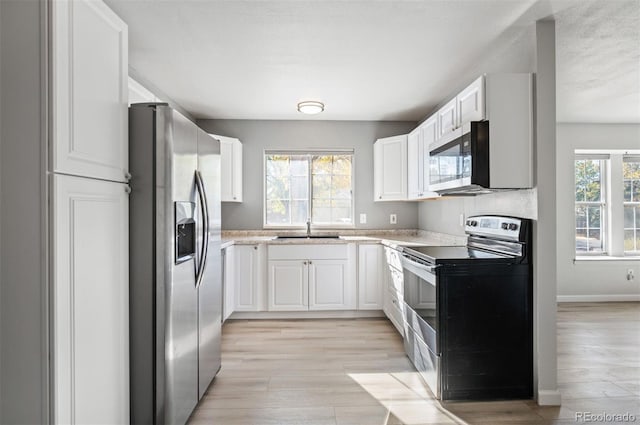 kitchen with sink, stainless steel appliances, light hardwood / wood-style floors, and white cabinets