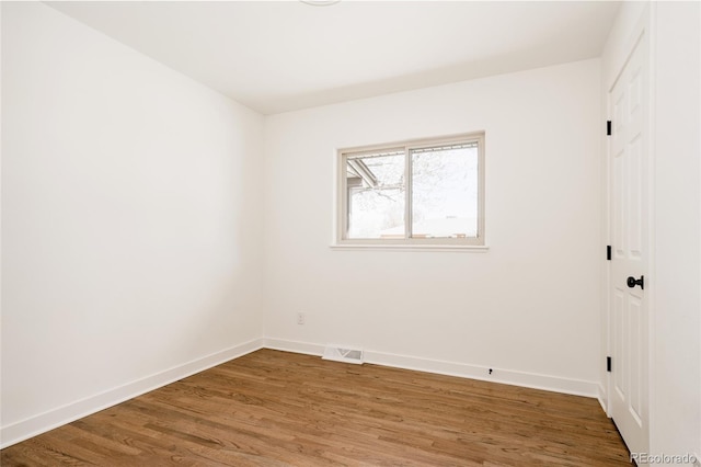 spare room featuring visible vents, baseboards, and wood finished floors