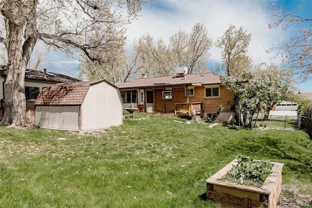 rear view of house featuring fence, brick siding, a storage shed, an outdoor structure, and a yard