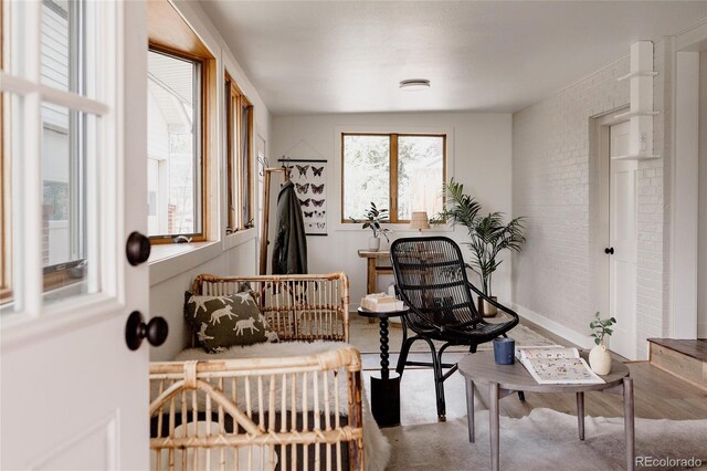living area with baseboards and brick wall