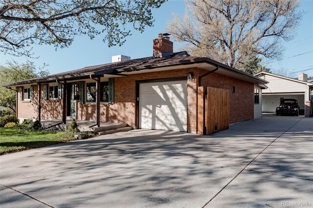 single story home with brick siding, an attached garage, and a chimney