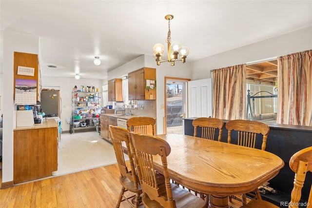 dining area featuring sink, a chandelier, and light hardwood / wood-style flooring