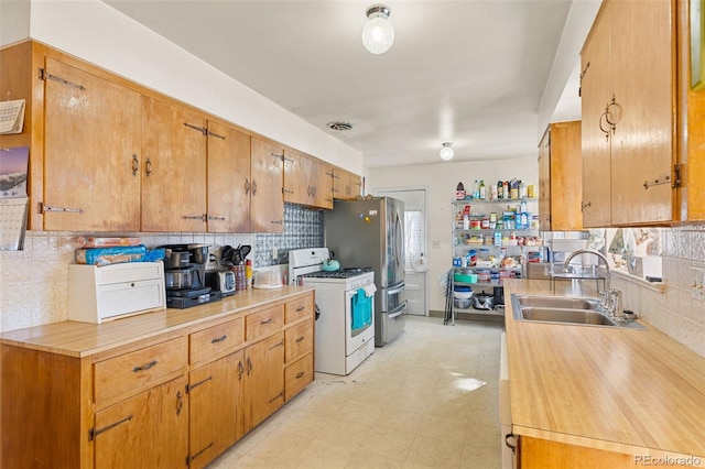 kitchen featuring white gas range, sink, and backsplash