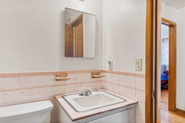 bathroom with vanity, tile walls, and toilet