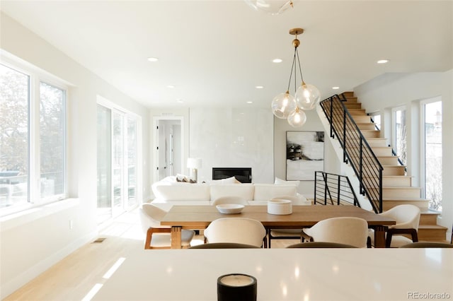 dining space with a healthy amount of sunlight, stairs, and a premium fireplace