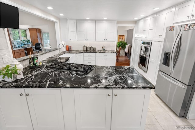 7330 Routt St, Arvada, CO 80005 - kitchen with appliances with stainless steel finishes, white cabinets, tasteful backsplash, dark stone counters, and recessed lighting