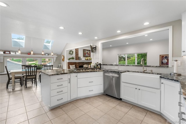 7330 Routt St, Arvada, CO 80005 - kitchen with appliances with stainless steel finishes, a skylight, decorative backsplash, white cabinets, and dark stone counters