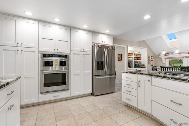 7330 Routt St, Arvada, CO 80005 - kitchen featuring stainless steel appliances, a skylight, white cabinets, dark stone counters, and light tile patterned flooring