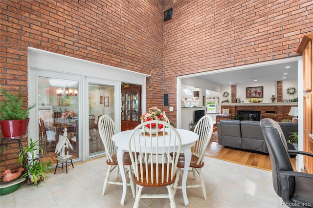 7330 Routt St, Arvada, CO 80005 - dining space with a towering ceiling, brick wall, a brick fireplace, and light tile patterned flooring