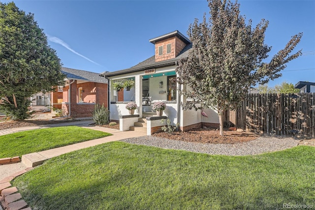 view of front facade with brick siding, a front yard, and fence