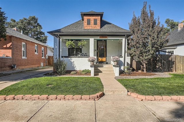 bungalow featuring a front lawn, a porch, fence, and roof with shingles