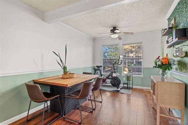 dining space with wood finished floors, ceiling fan, a textured ceiling, ornamental molding, and baseboards