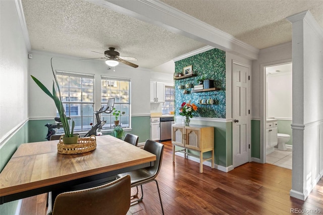 dining area featuring a ceiling fan, decorative columns, a textured ceiling, wood finished floors, and crown molding