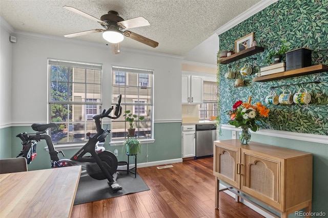 exercise area featuring dark wood finished floors, healthy amount of natural light, a ceiling fan, ornamental molding, and baseboards