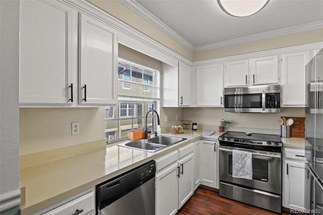 kitchen featuring appliances with stainless steel finishes, a sink, ornamental molding, white cabinets, and light countertops