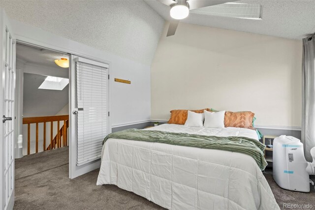carpeted bedroom with vaulted ceiling, a textured ceiling, and a ceiling fan