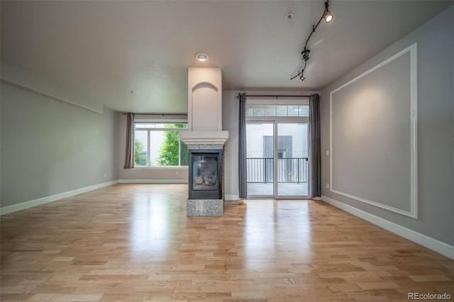 unfurnished living room with track lighting and light hardwood / wood-style flooring