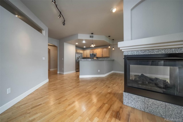 living room with light wood-type flooring, rail lighting, and a tiled fireplace