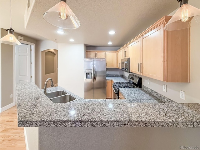 kitchen featuring appliances with stainless steel finishes, a textured ceiling, sink, light brown cabinets, and decorative light fixtures