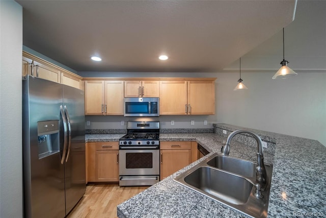 kitchen featuring light brown cabinets, sink, light wood-type flooring, appliances with stainless steel finishes, and decorative light fixtures