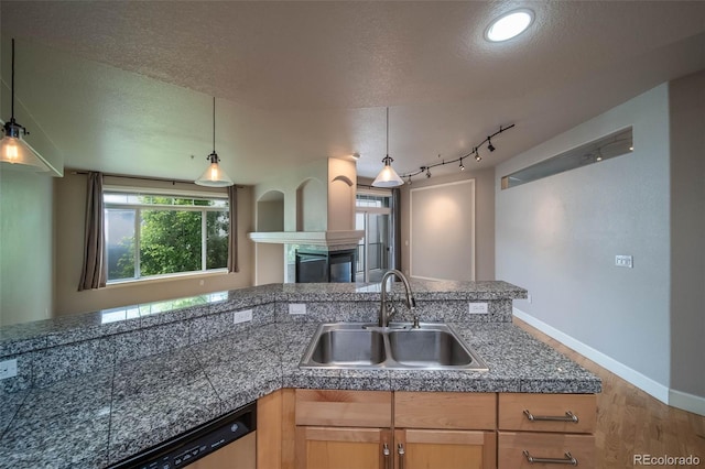 kitchen featuring a textured ceiling, hanging light fixtures, a healthy amount of sunlight, and sink