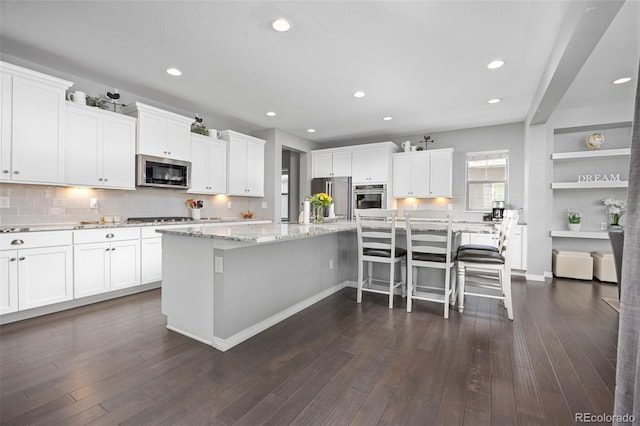525 Grenville Cir, Erie, CO 80516 - kitchen featuring stainless steel appliances, white cabinetry, a spacious island, light stone counters, and recessed lighting